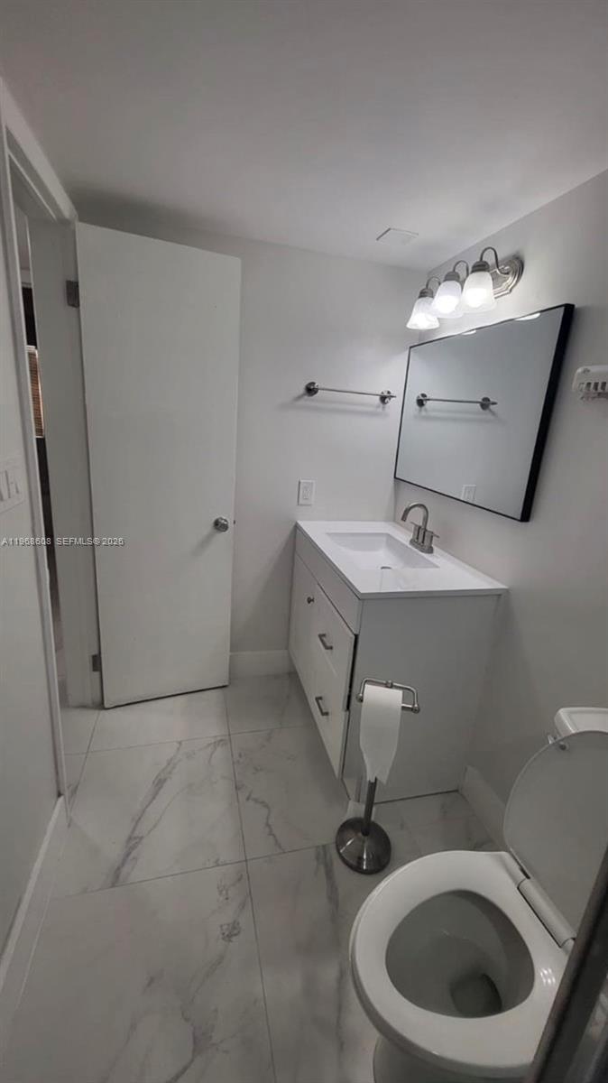 5425 Southwest 77th Court, Unit 102D Miami, FL 33155 - Photo 18 of 22 a bathroom with a sink mirror vanity and toilet