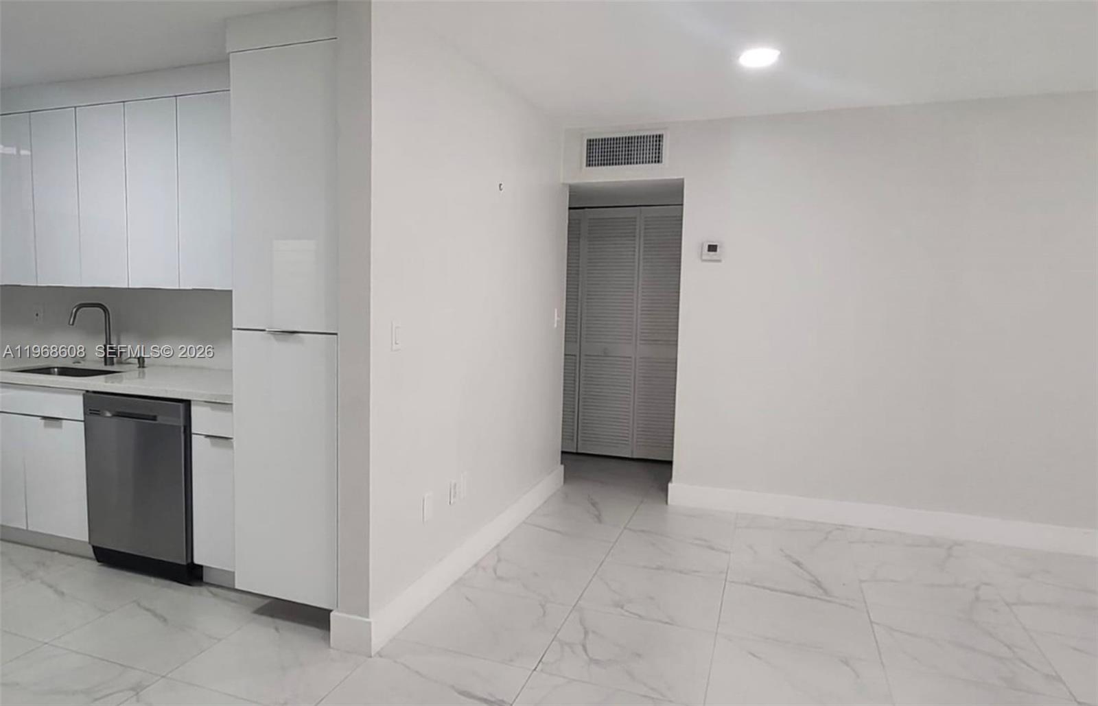 5425 Southwest 77th Court, Unit 102D Miami, FL 33155 - Photo 7 of 22 a kitchen with a refrigerator and white cabinets