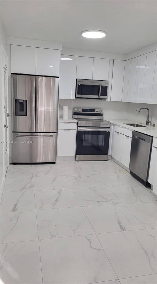 5425 Southwest 77th Court, Unit 102D Miami, FL 33155 - Photo 8 of 22 a kitchen with a refrigerator sink and cabinets