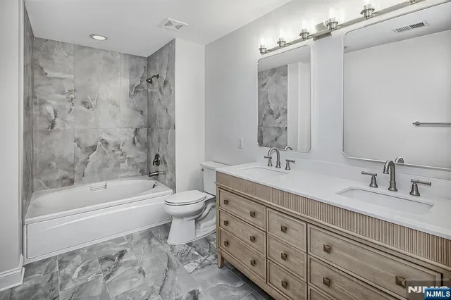 a bathroom with a double vanity sink mirror toilet and bathtub