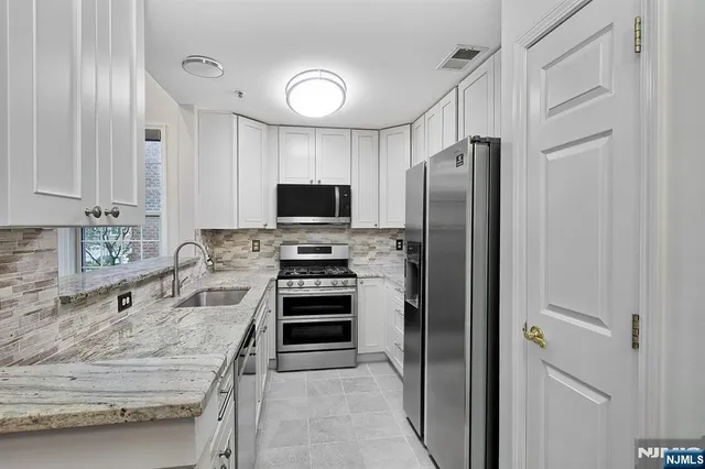 a kitchen with stainless steel appliances granite countertop a refrigerator stove and sink