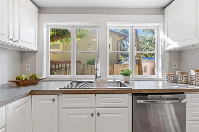 a white kitchen with granite countertop a sink and a window
