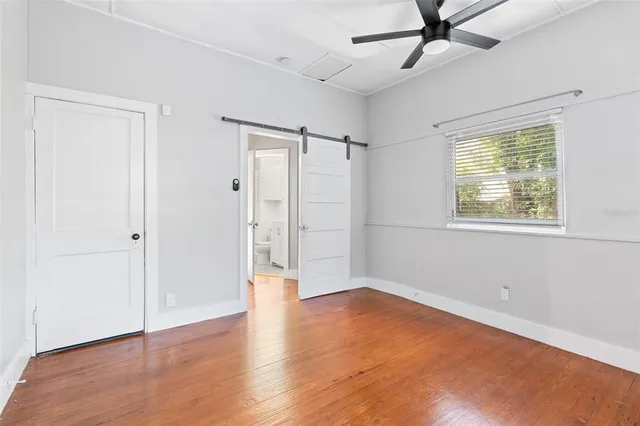a view of an empty room with a window and wooden floor