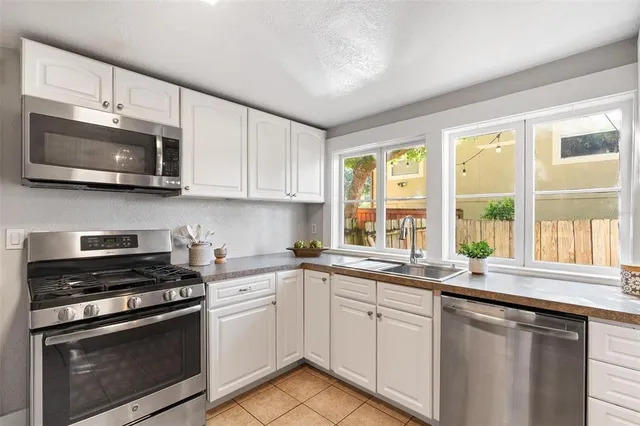 a kitchen with stainless steel appliances white cabinets a sink and a stove top oven
