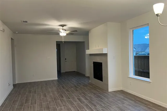 a view of a livingroom with a fireplace a ceiling fan and wooden floor