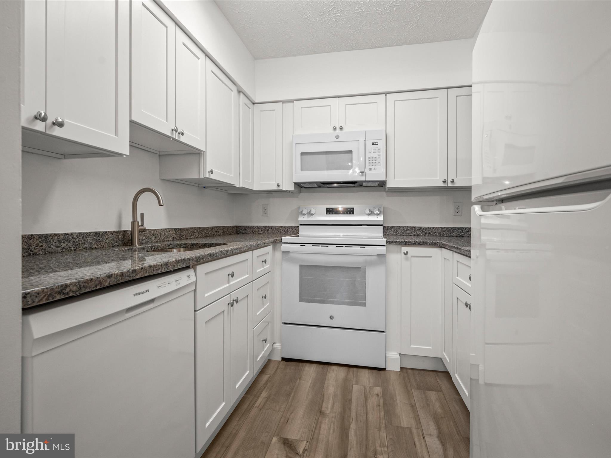7607 Weather Worn Way, Unit A Columbia, MD 21046 - Photo 17 of 36 a kitchen with granite countertop white cabinets and white appliances