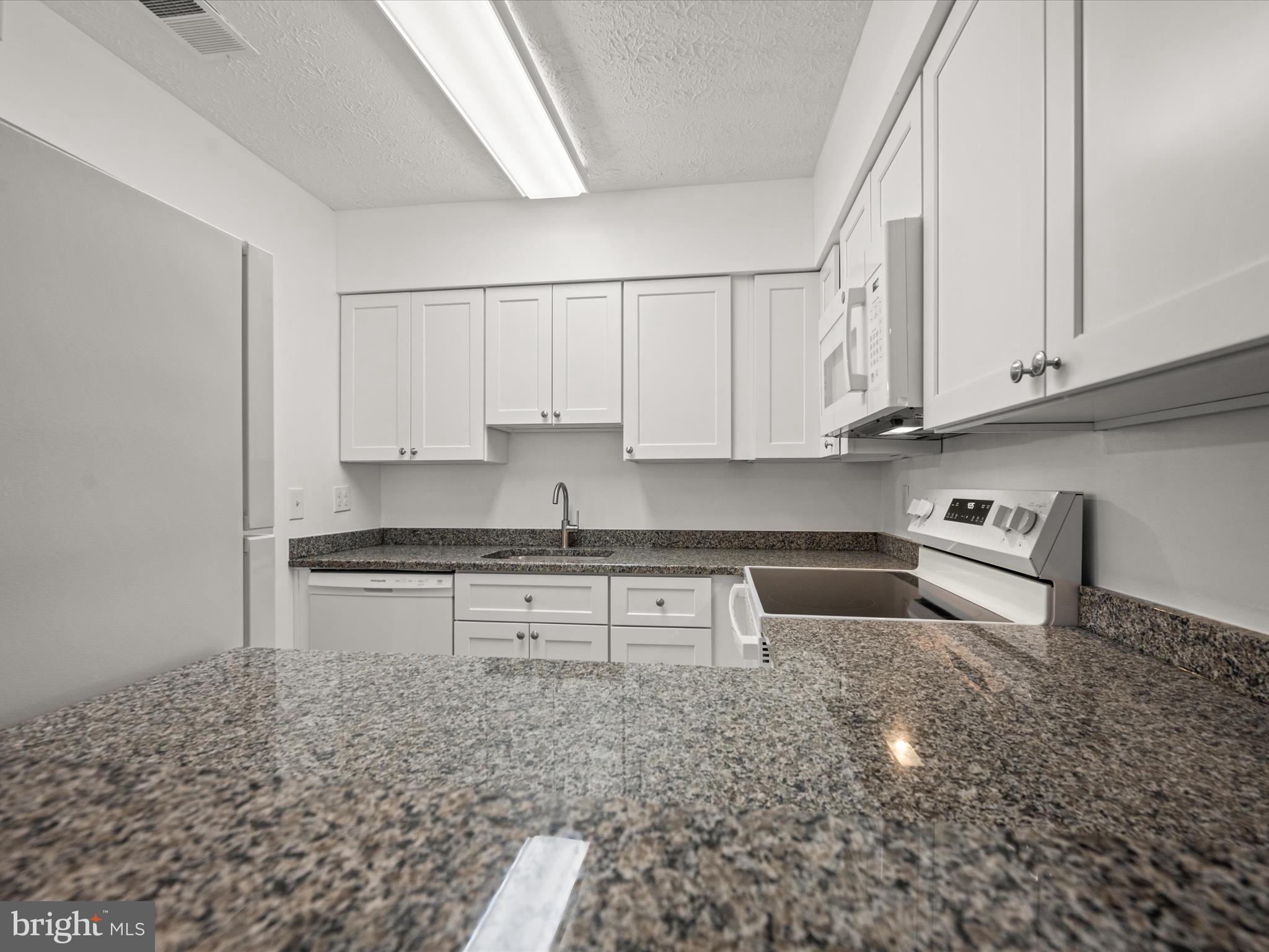 7607 Weather Worn Way, Unit A Columbia, MD 21046 - Photo 20 of 36 a kitchen with stainless steel appliances granite countertop a sink stove and cabinets