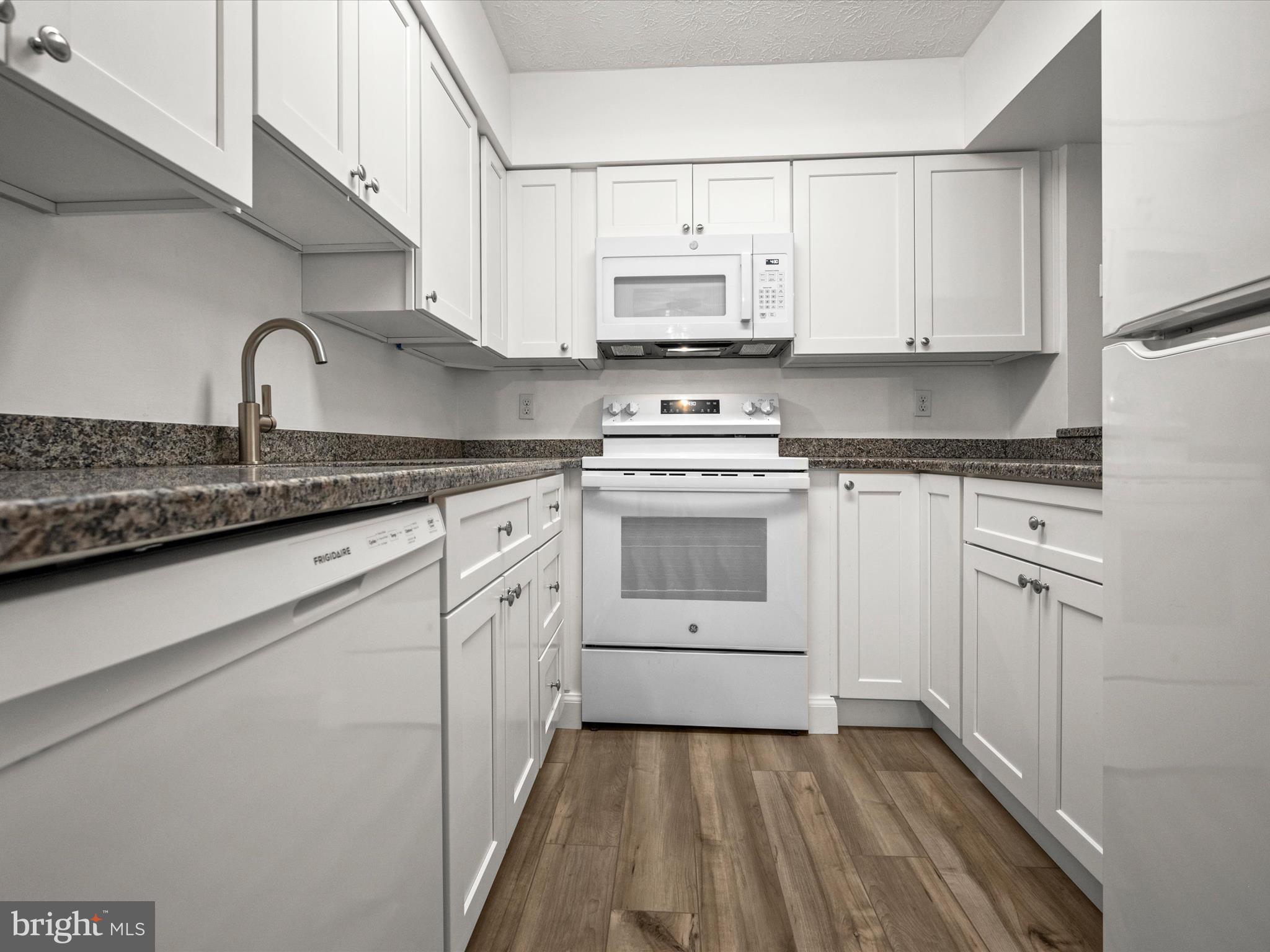 7607 Weather Worn Way, Unit A Columbia, MD 21046 - Photo 5 of 36 a kitchen with stainless steel appliances granite countertop white cabinets sink and white appliances