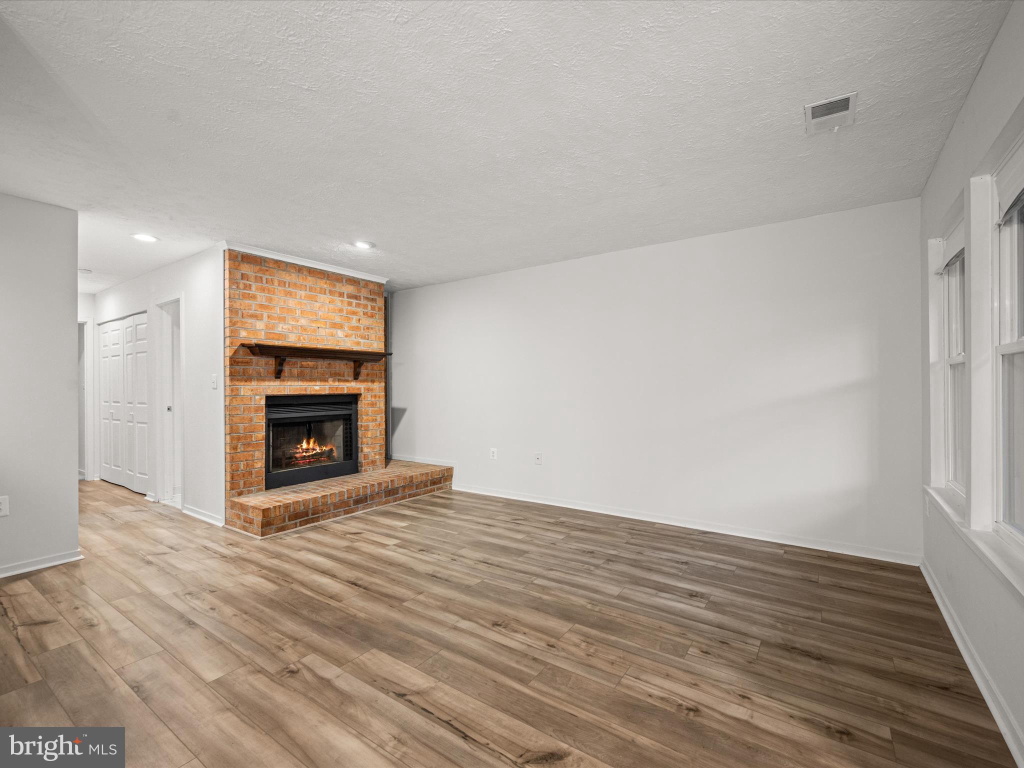 7607 Weather Worn Way, Unit A Columbia, MD 21046 - Photo 8 of 36 an empty room with wooden floor a fireplace and windows
