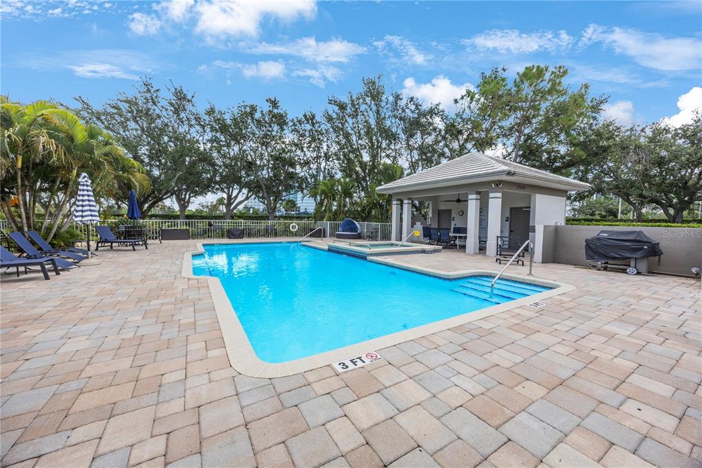 13606 Eagles Walk Drive Clearwater, FL 33762 - Photo 28 of 28 a view of a swimming pool with lawn chairs under an umbrella