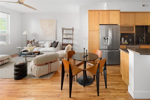 a kitchen with stainless steel appliances kitchen island granite countertop a table chairs and a refrigerator