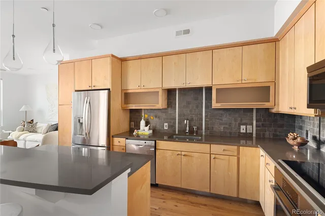 a kitchen with stainless steel appliances granite countertop a sink a stove and a wooden cabinets