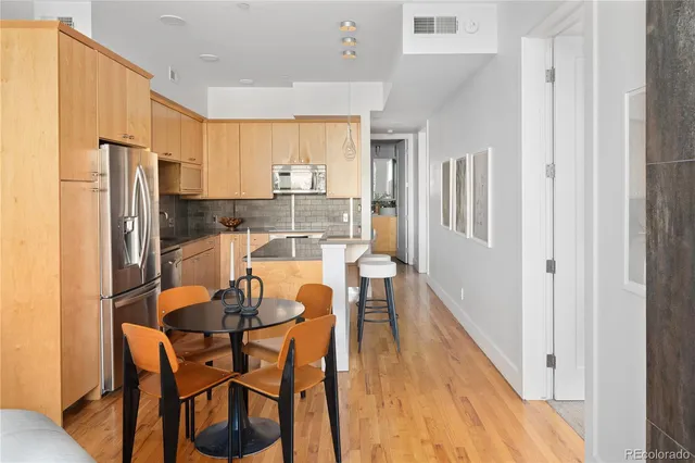 a kitchen with stainless steel appliances a refrigerator a stove a dining table and chairs