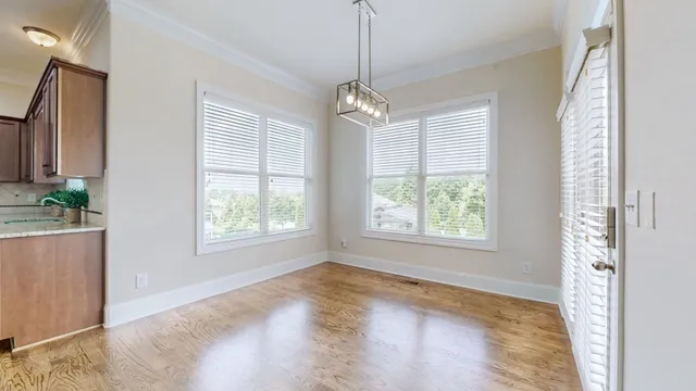 a view of a hallway with wooden floor table and chairs