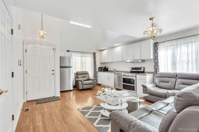 a kitchen with stainless steel appliances kitchen island granite countertop a refrigerator a sink dishwasher a dining table and chairs with wooden floor