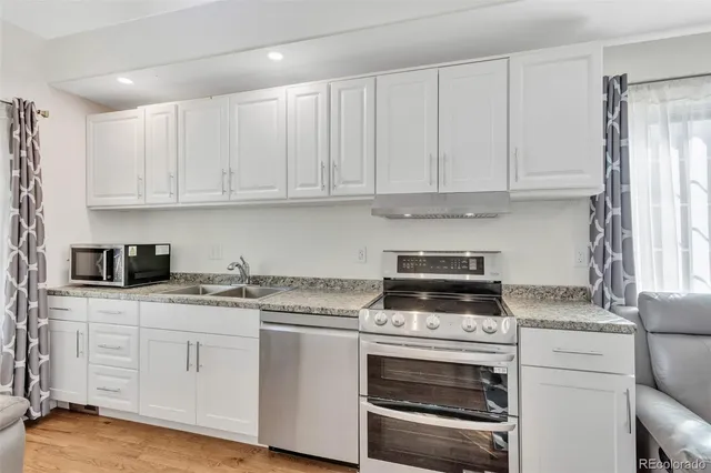 a kitchen with granite countertop white cabinets and white appliances