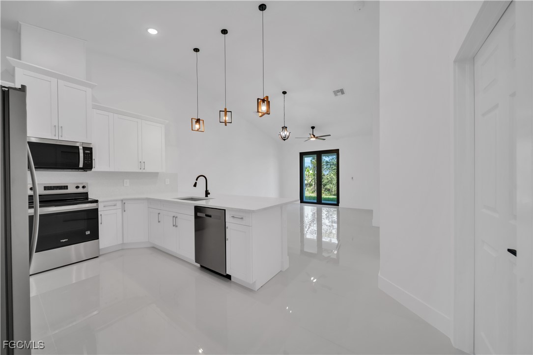 1112 Eisenhower Boulevard Lehigh Acres, FL 33974 - Photo 19 of 35 a large white kitchen with stainless steel appliances