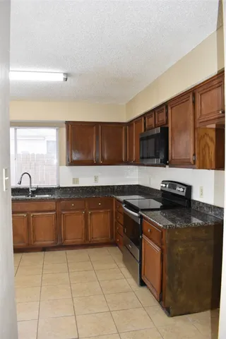 a large kitchen with granite countertop a stove top oven microwave and cabinets