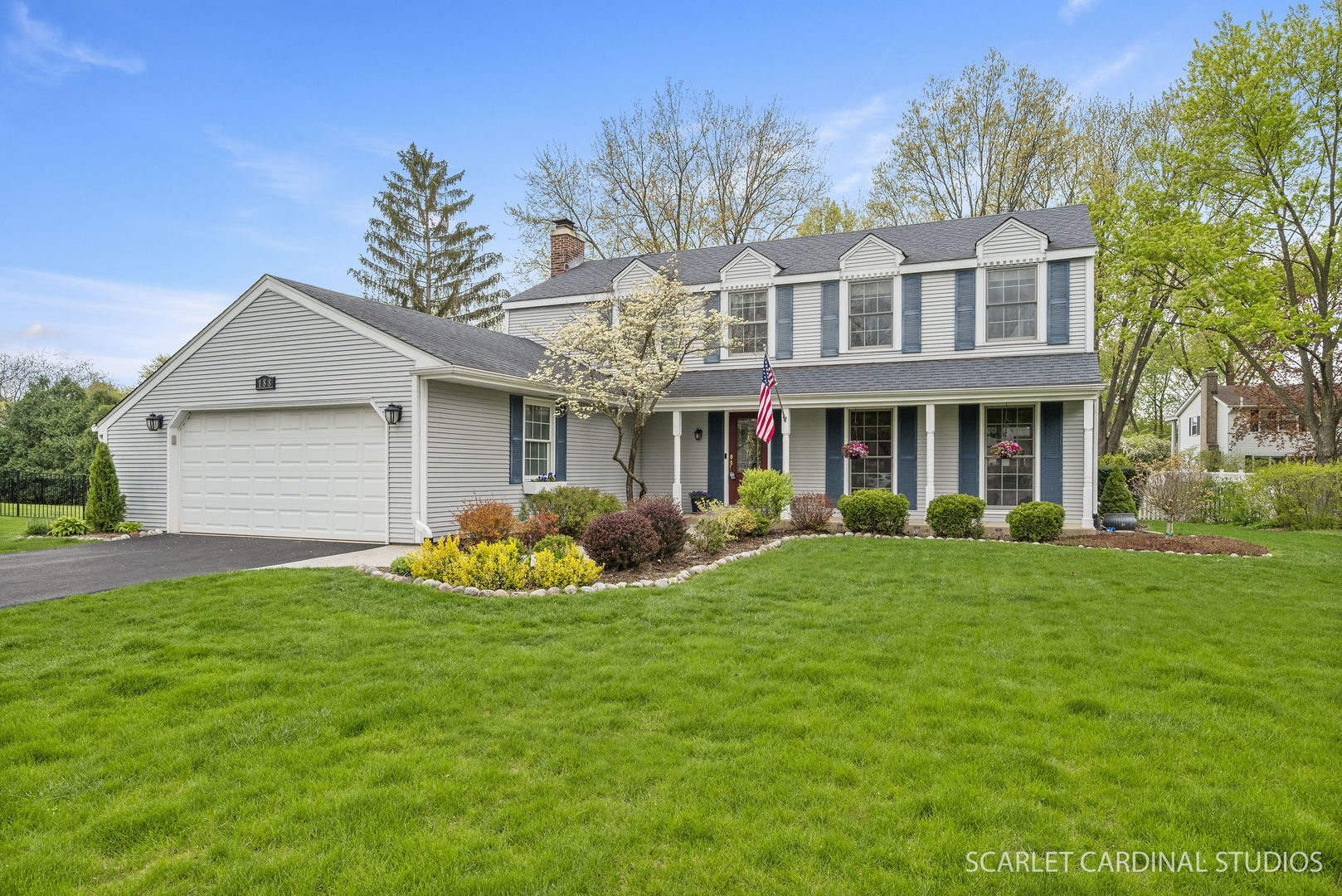 a front view of a house with a garden and trees