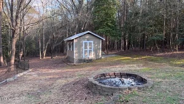 a view of a wooden house with a yard and large trees