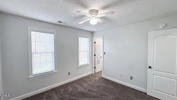 an empty room with window and chandelier fan