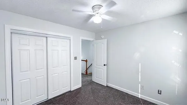 an empty room with windows and chandelier fan