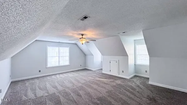 an empty room with a chandelier fan and windows