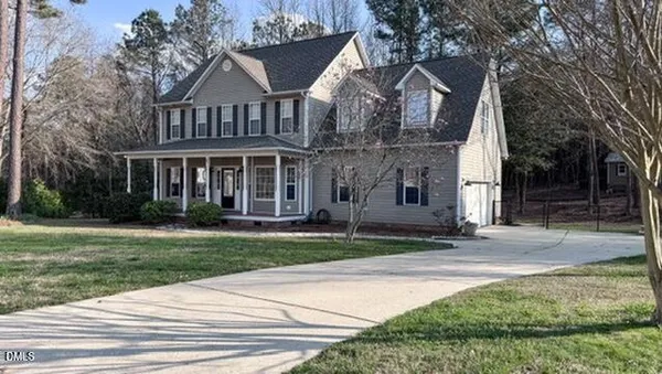 a front view of a house with a garden and tree