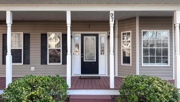 front view of a brick house with a large window and potted plants