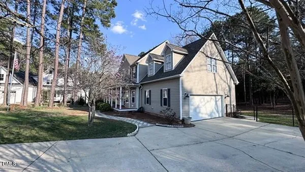 a view of a white house with a large tree and plants