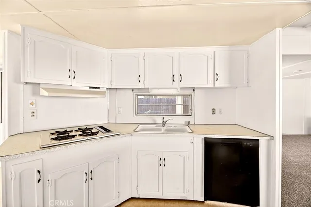 a kitchen with granite countertop a sink cabinets and stainless steel appliances