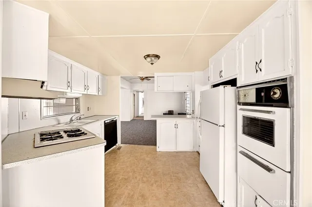 a kitchen with refrigerator a stove and white cabinets