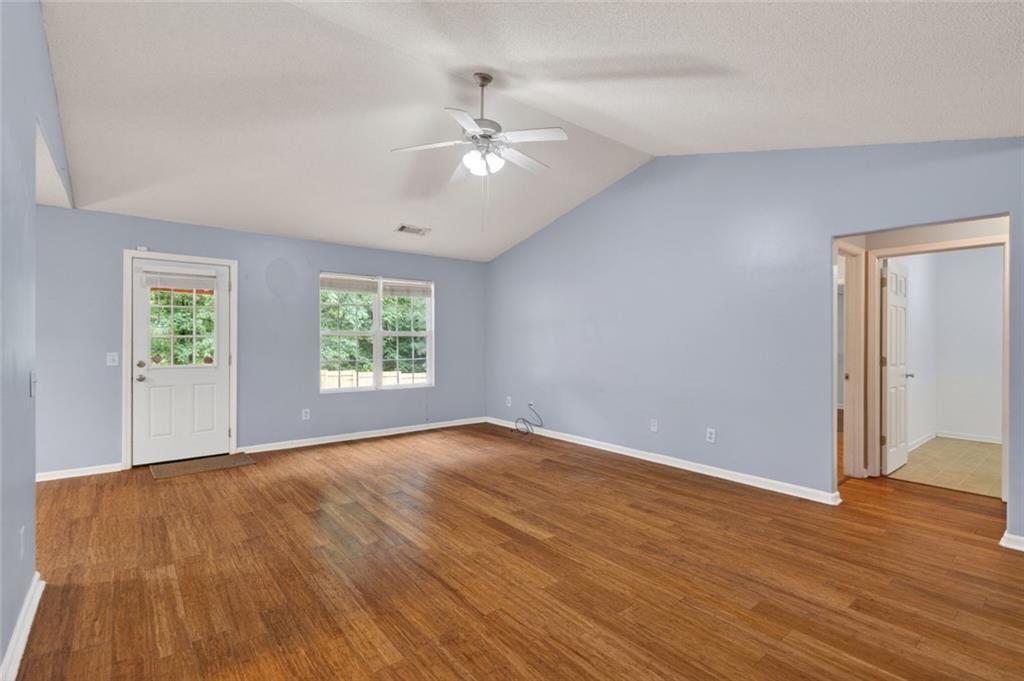 466 Raymond Drive Winder, GA 30680 - Photo 12 of 33 an empty room with wooden floor chandelier fan and windows