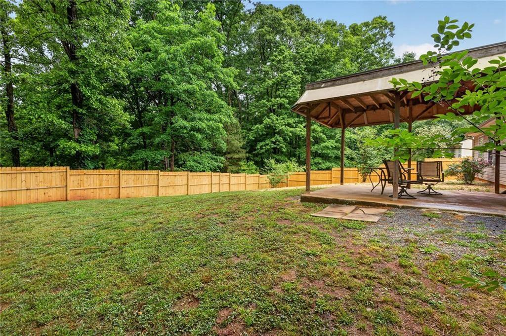 466 Raymond Drive Winder, GA 30680 - Photo 26 of 33 a view of a garden with lawn chairs under an umbrella