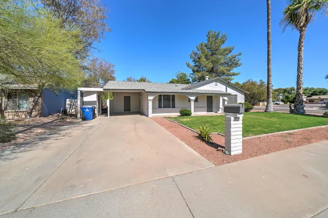 front view of a house with a yard and palm trees
