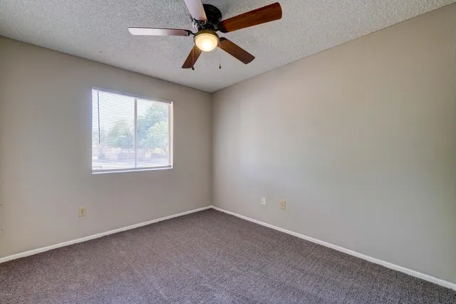 an empty room with a window and a fan