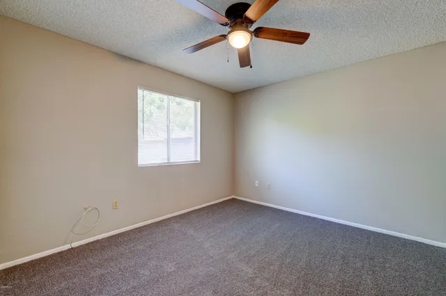 an empty room with chandelier fan and windows