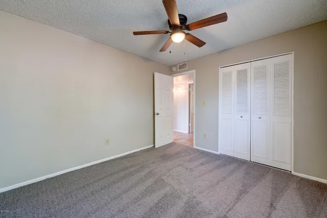 an empty room with ceiling fan and window