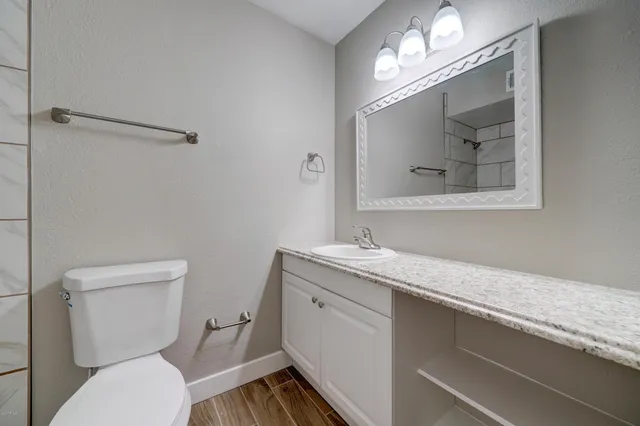 a bathroom with a granite countertop toilet a sink and mirror