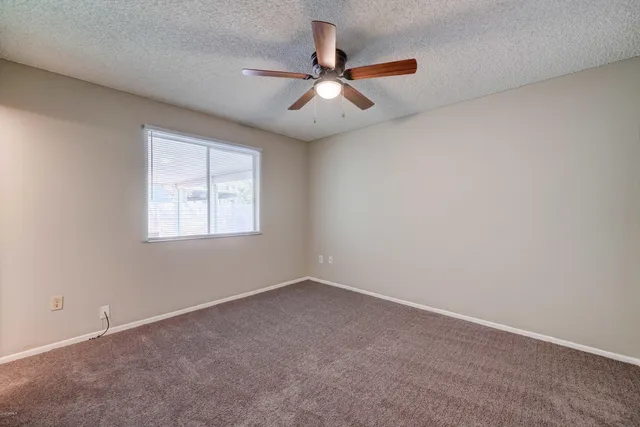 an empty room with ceiling fan and windows