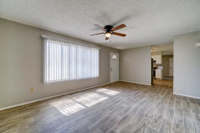 a view of empty room with wooden floor and fan