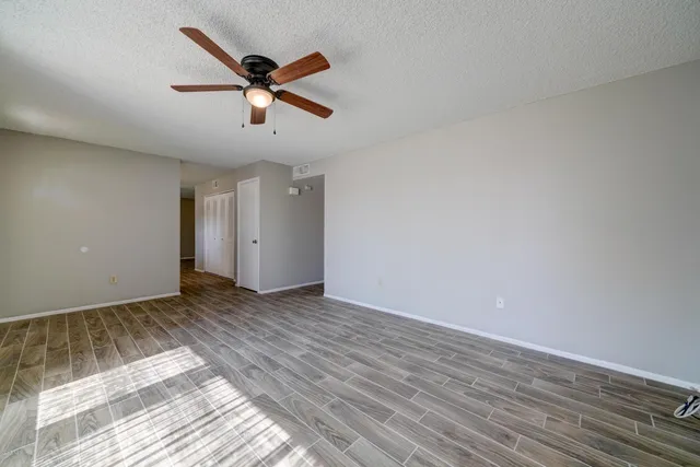 a view of empty room with wooden floor and ceiling fan
