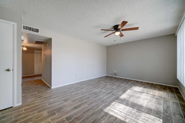 an empty room with wooden floor and fan