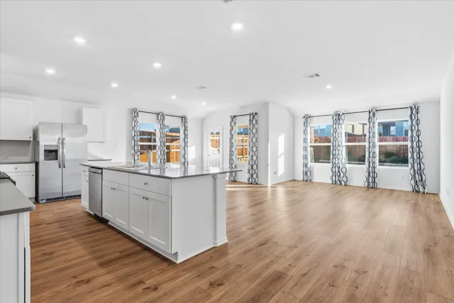 a kitchen with stainless steel appliances wooden floors and white cabinets