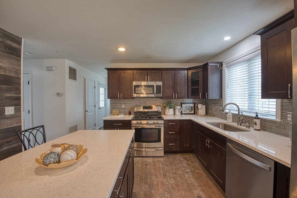438 Smith Street Fall River, MA 02721 - Photo 4 of 31 a kitchen with stainless steel appliances granite countertop a sink a stove a refrigerator a microwave oven with a dining table and chairs