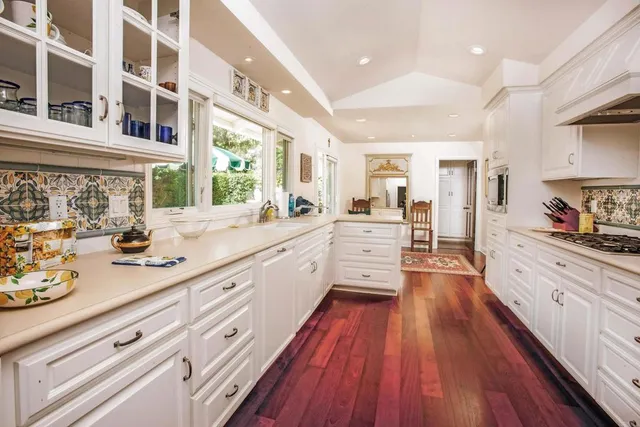 a large kitchen with a lot of counter space and wooden floor