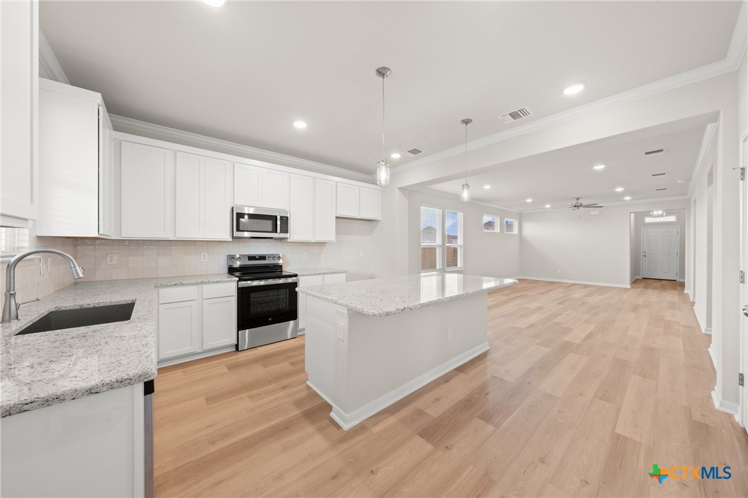 8024 Pineridge Way Temple, TX 76502 - Photo 15 of 32 a large white kitchen with a refrigerator a stove top oven a sink dishwasher and white cabinets with wooden floor