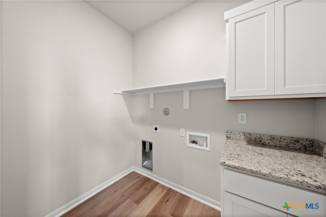 8024 Pineridge Way Temple, TX 76502 - Photo 24 of 32 a kitchen with granite countertop white cabinets and a wooden floor
