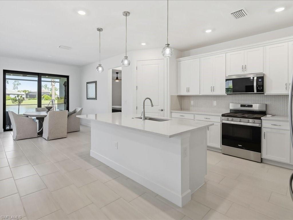 1937 Don Benito Way Naples, FL 34120 - Photo 6 of 27 Kitchen with stainless steel appliances, decorative light fixtures, backsplash, white cabinetry, and recessed lighting