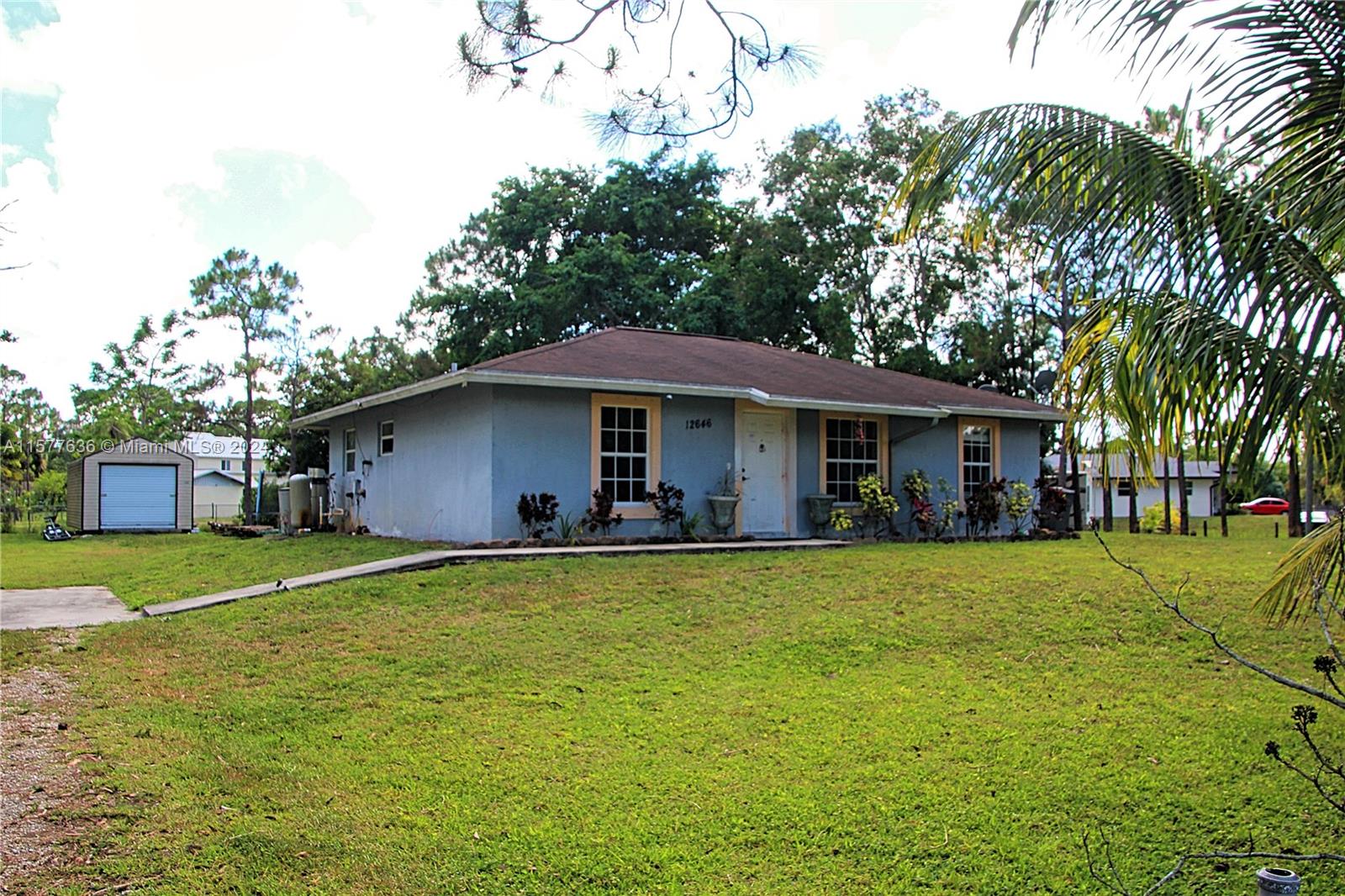 12646 55th Road North West Palm Beach, FL 33411 - Photo 1 of 10 a front view of a house with a garden and trees